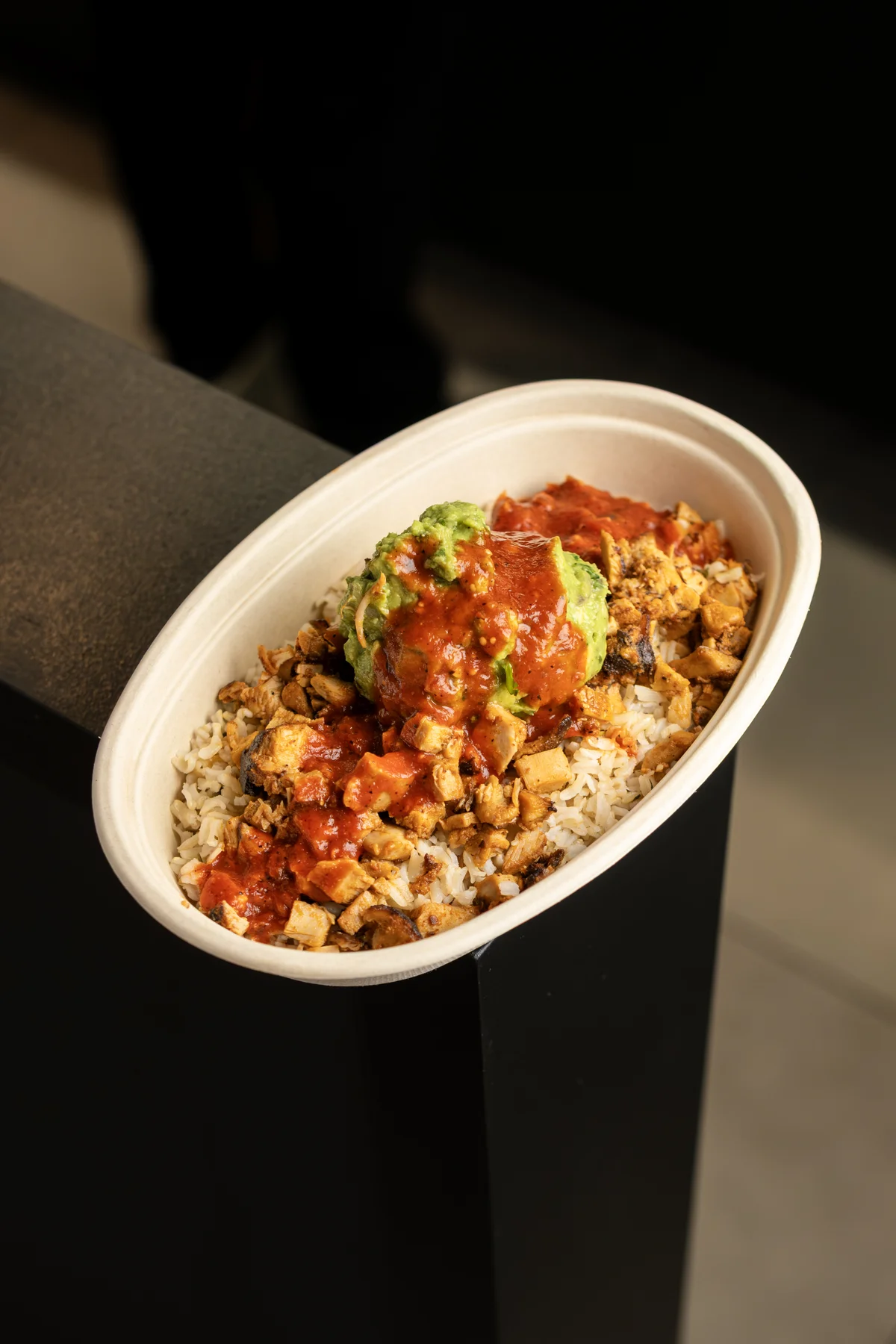 Rice bowl with chicken and guacamole in takeaway packaging