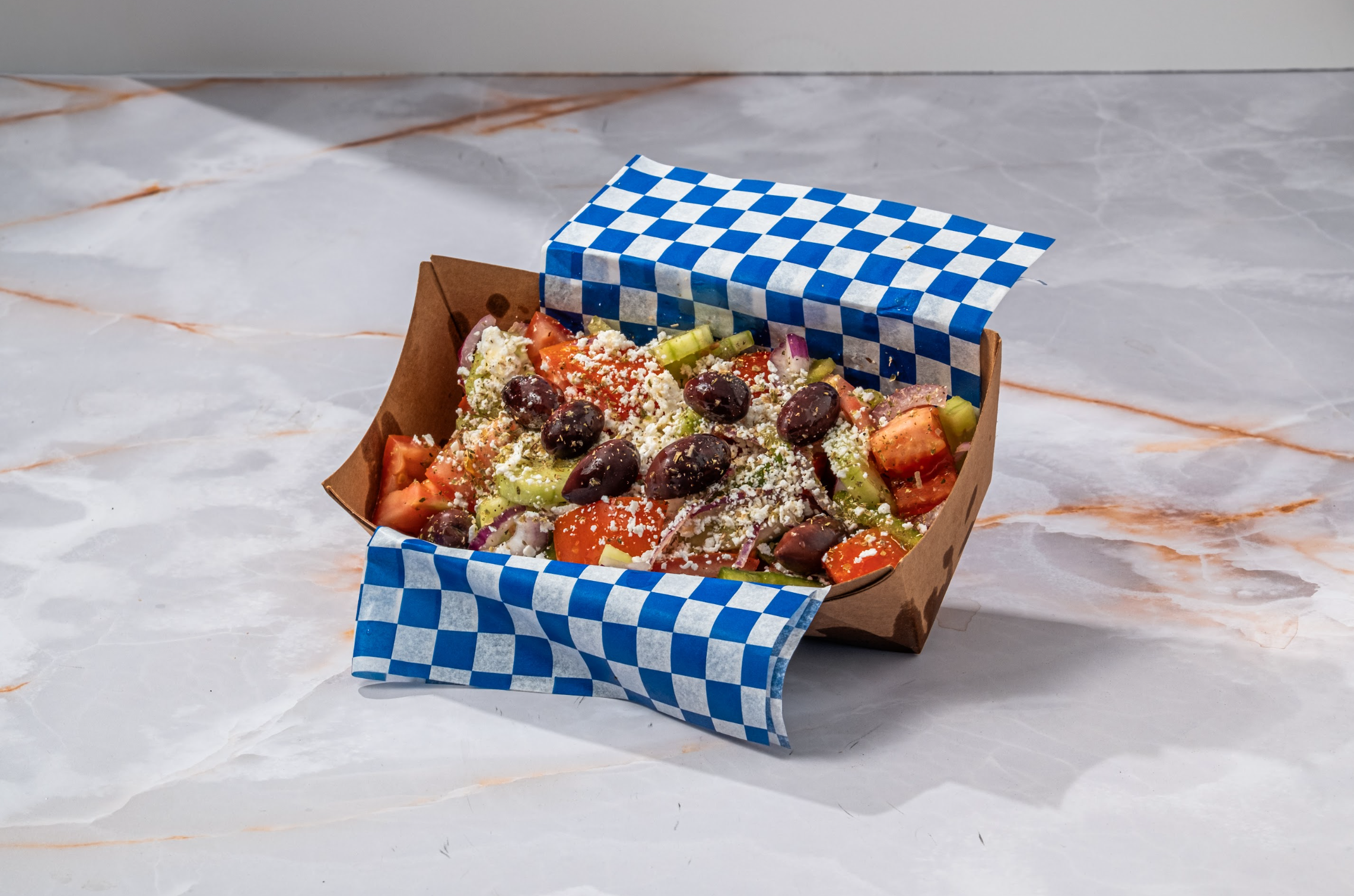 Greek salad with feta, olives and vegetables in takeaway packaging